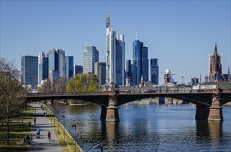 Walkers on the banks of the Main in front of the skyline of Frankfurt city centre with the banking district