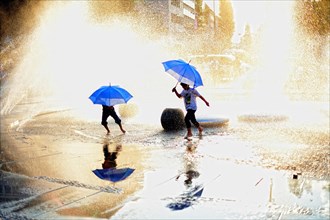 Children with umbrellas walking through water