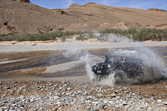 Off-road vehicle crosses a river in the Middle Atlas