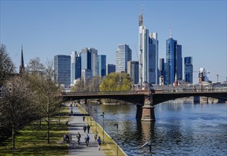 Walkers on the banks of the Main in front of the skyline of Frankfurt city centre with the banking district