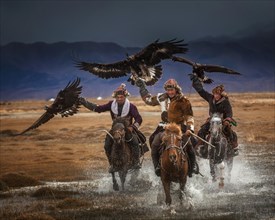 Mongolian eagle hunters. Three Kazakhs on horseback with trained eagles. Bayan-Ulgii province