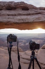 Cameras with view through Mesa Arch at sunrise