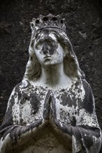 Weathered figure of the Virgin Mary on a grave
