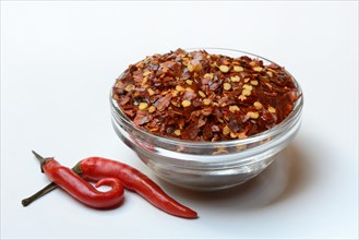 Chili flakes in glass bowl and chilli peppers