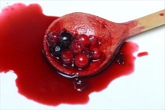 Boiled red and black currants in wooden spoon