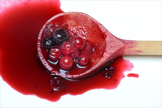 Boiled red and black currants in wooden spoon