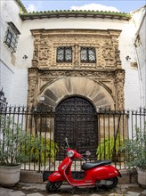 Red scooter Piaggio Vespa in front of an entrance door