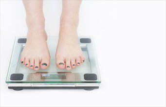 Woman in a weighing machine with white background