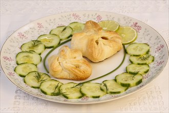Puff pastry pocket enriched with cucumbers and slices of lime on plates