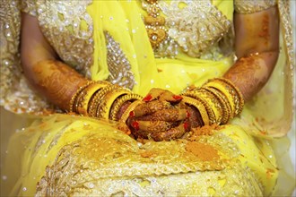Hand of a bride painted with henna and fresh turmeric paste on the eve of the wedding