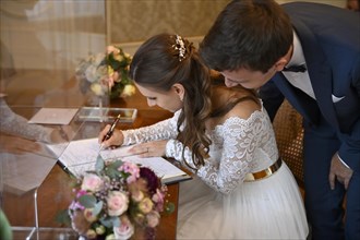 Bridal couple signs marriage certificate at the registry office