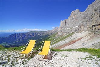 Two sun loungers in front of a mountain range with high mountain scenery