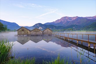 Boathouses and jetty in Lake Kochel near Schlehdorf in the morning light