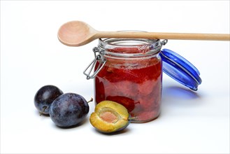 Plum compote in glass with cooking spoon