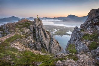 Woman sitting on rocky outcrop Summit of Hoven at sunset