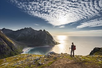 Hiker at the summit overlooking Kvalvika beach and wide sea