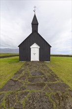 Traditional black church with white wooden door in barren landscape
