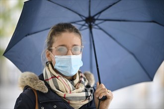 Woman with face mask and umbrella