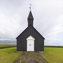 Traditional black church with white wooden door and stone wall