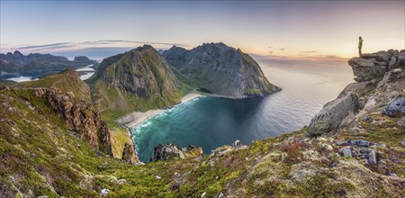 Tiny person on rocky outcrop overlooks Kvalvika beach and wide sea