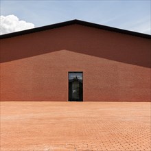 Windowless red brick building in the shape of a warehouse