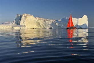 Red sailing boat in front of icebergs