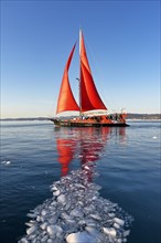 Red sailing boat in drift ice