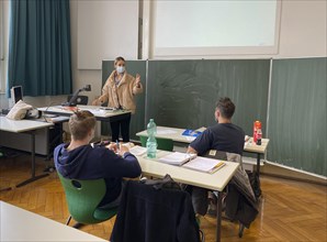Teacher with thick winter jacket and face mask in classroom teaching