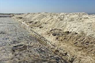 Harvested rock salt at the edge of an evaporation basin of a salt works