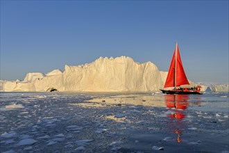 Red sailing boat in front of icebergs