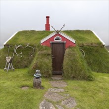 Traditional peat house Lindarbakki overgrown with grass and antlers in the red gable