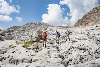 Three hikers in a landscape of washed-out karst rocks