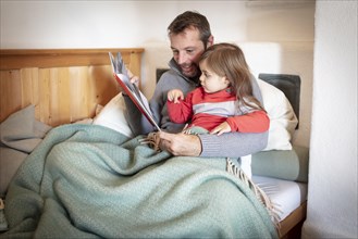 Father reading aloud with daughter