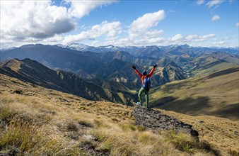 Hiker stretches out his arms in the air