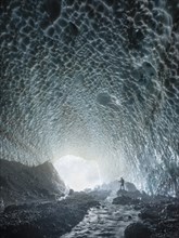 Mountaineer in the ice chapel with meltwater stream
