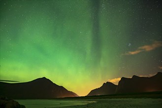 Northern lights in front of a starry sky on the beach