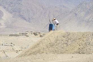 Worker with wheelbarrow in the ruins of Caral