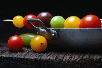 Various cherry tomatoes on wooden skewers on peel