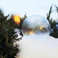 Frozen soap bubble in snow forms ice crystals