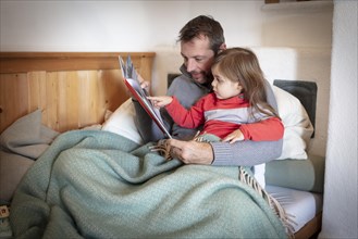 Father reading aloud with daughter