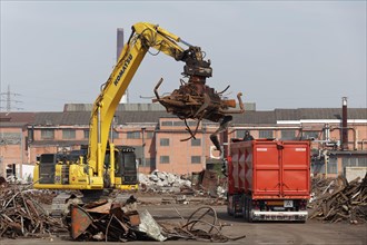 Excavator loads metal scrap onto truck