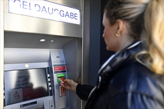 Woman introduces ec-card at the cash dispenser of a savings bank