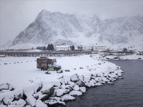 Motorhome painted as a mountain hut in snowfall at the parking lot in front of a fjord
