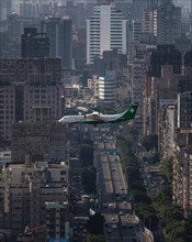 Uni Air plane flies over urban area with streets and skyscrapers