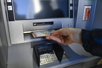 Woman draws 100 EURO cash at the cash machine of a savings bank