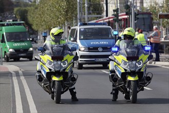Two policemen on motorcycles and crew cars