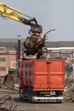 Excavator loads metal scrap onto truck