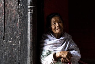 Portrait of an older woman looking out of a doorway