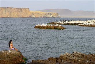 Woman sitting on a rock in Paracas National Reserve