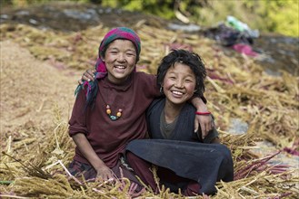 Two happily laughing children sitting in a pile of pearl millet